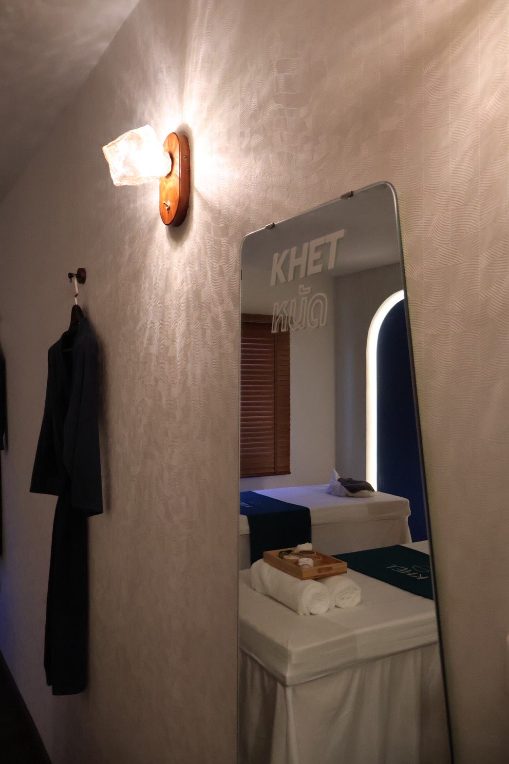 KHET Massage — room detail with KHET mirror and crystal wall lamp